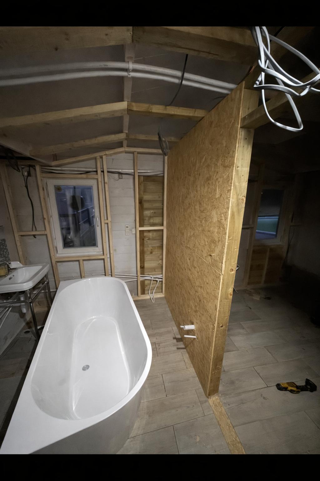 Cabin bathroom mid-build with timber framing, OSB partition and freestanding bath placed