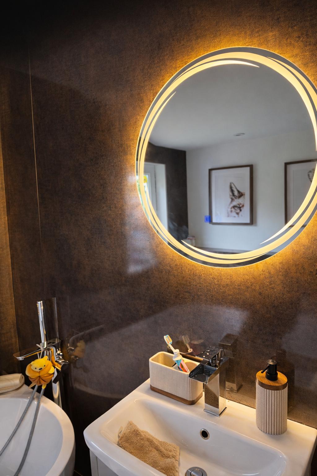 LED backlit round mirror with dark textured wall panels and modern basin