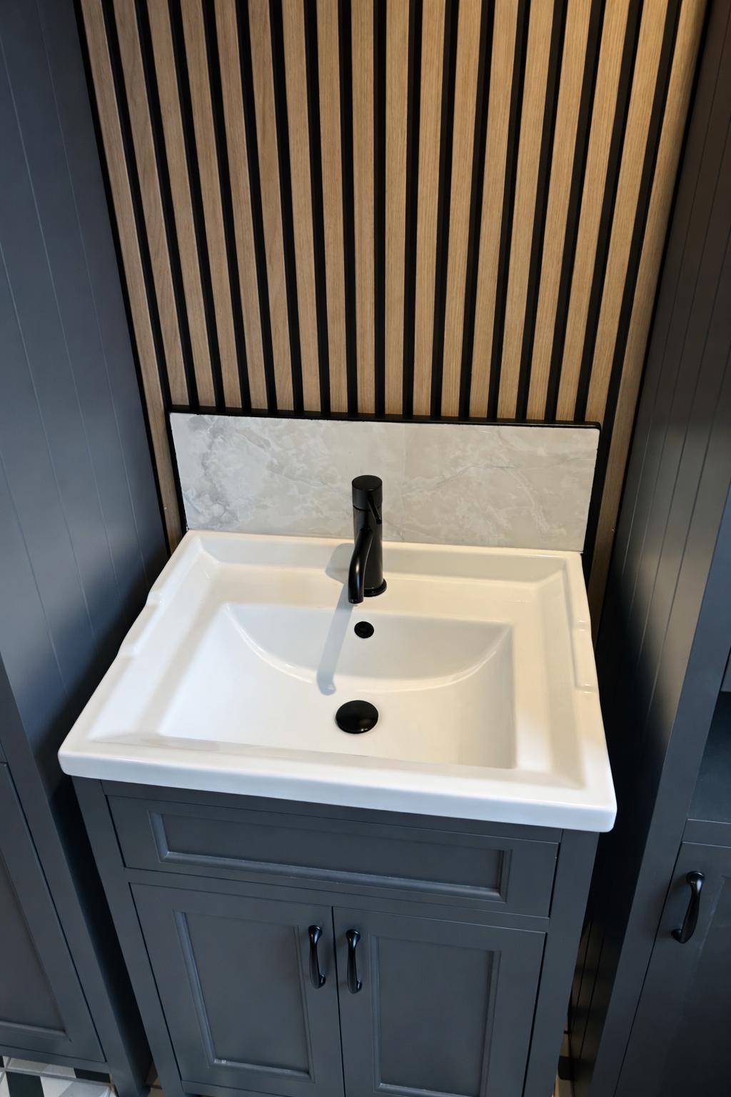 Grey vanity unit with marble backsplash and matte black tap